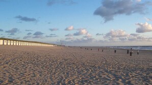 A wide sandy beach with a row of white buildings along the shore. - Lovely villa on the edge of the forest (Den Burg)