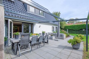 A modern house with a patio, outdoor seating, and potted plants. - Lovely villa on the edge of the forest (Den Burg)