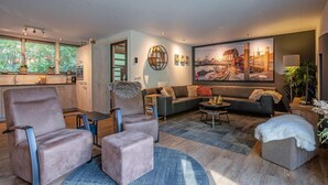A modern living room with a sofa, armchairs, a coffee table, and a large painting on the wall. - Lovely villa on the edge of the forest (Den Burg)