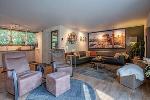 A modern living room with a sofa, armchairs, a coffee table, and a large painting on the wall. - Lovely villa on the edge of the forest (Den Burg)