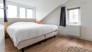 Ein Schlafzimmer mit Bett, Fenster und Heizkörper.