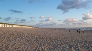 Ein breiter Sandstrand mit einer Reihe weißer Gebäude an der linken Seite.