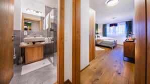A modern bathroom with a wooden vanity, a mirror, and a shower area. - Modern apartment in Neukirchen (Neukirchen am Großvenediger)