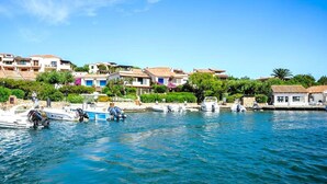 A coastal village with boats docked along the waterfront, surrounded by traditional Mediterranean-style buildings. - Rotondo Escape with Terrace (Porto Rotondo (SS))