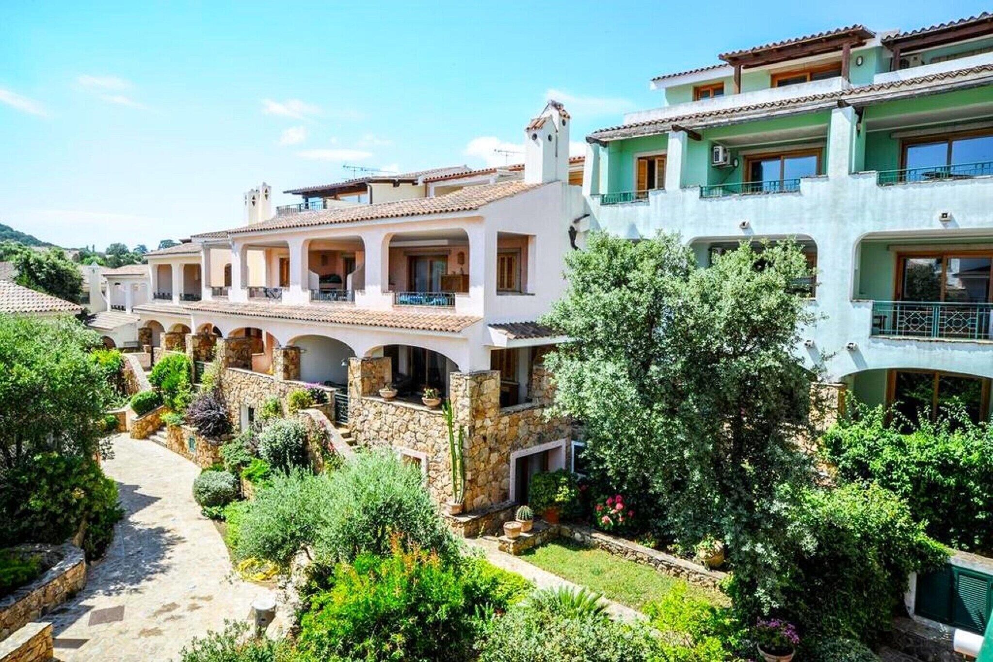 A row of Mediterranean-style buildings with stone and stucco exteriors, terracotta roofs, and balconies.