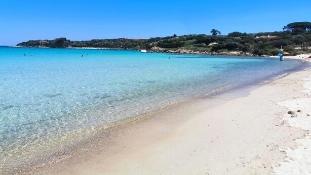 A beach with clear turquoise water, a sandy shore, and a few people. - Rotondo Escape with Terrace (Porto Rotondo (SS))