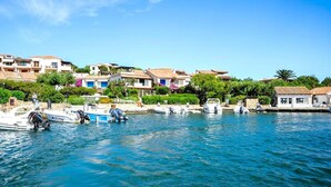 Uma vila costeira com barcos atracados ao longo da orla, cercada por edifícios tradicionais com telhados de terracota.