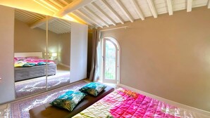 A bedroom with a large bed, a mirror, and a window.