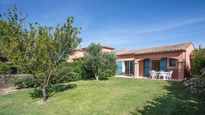 Una casa con tetto in tegole, un piccolo prato e un patio con mobili da esterno.