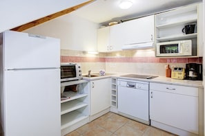 Eine kleine Küche mit weißen Schränken, einer Mikrowelle, einem Toaster und einem Geschirrspüler.