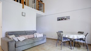 A living room with a grey sofa, a dining table with chairs, a staircase, and a framed picture on the wall. - Family Villa Near Lac de Jouarres (Homps)