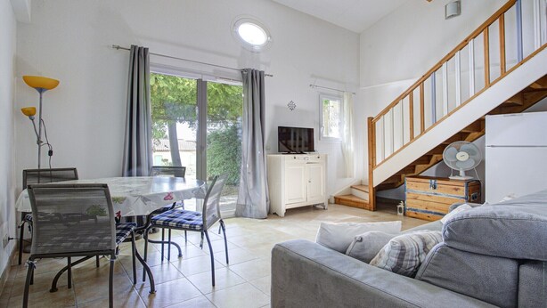 A spacious living area with a dining table, chairs, a sofa, a staircase, and a television. - Family Villa Near Lac de Jouarres (Homps)