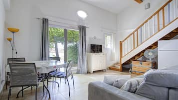 Un grand espace de vie comprenant une table à manger, des chaises, un canapé, un escalier et un téléviseur.