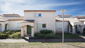 A row of Mediterranean-style buildings with terracotta roofs, green shutters, and a central entrance with a green door. - Family Villa Near Lac de Jouarres (Homps)