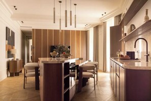 A modern kitchen with a central island, pendant lighting, and a dining area with chairs. - Luxury A/C Apt - 6P/3BDR - Arc de Triomphe (Paris)
