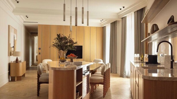 Une cuisine moderne dotée d’un îlot central, de luminaires suspendus et d’un coin repas avec des chaises.