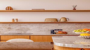 Une cuisine moderne avec un plan de travail en marbre, des armoires en bois et une table de salle à manger ronde.