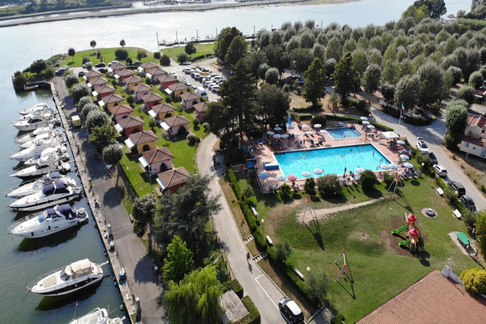 Una vista aerea di una marina con imbarcazioni ormeggiate, una piscina e ville.