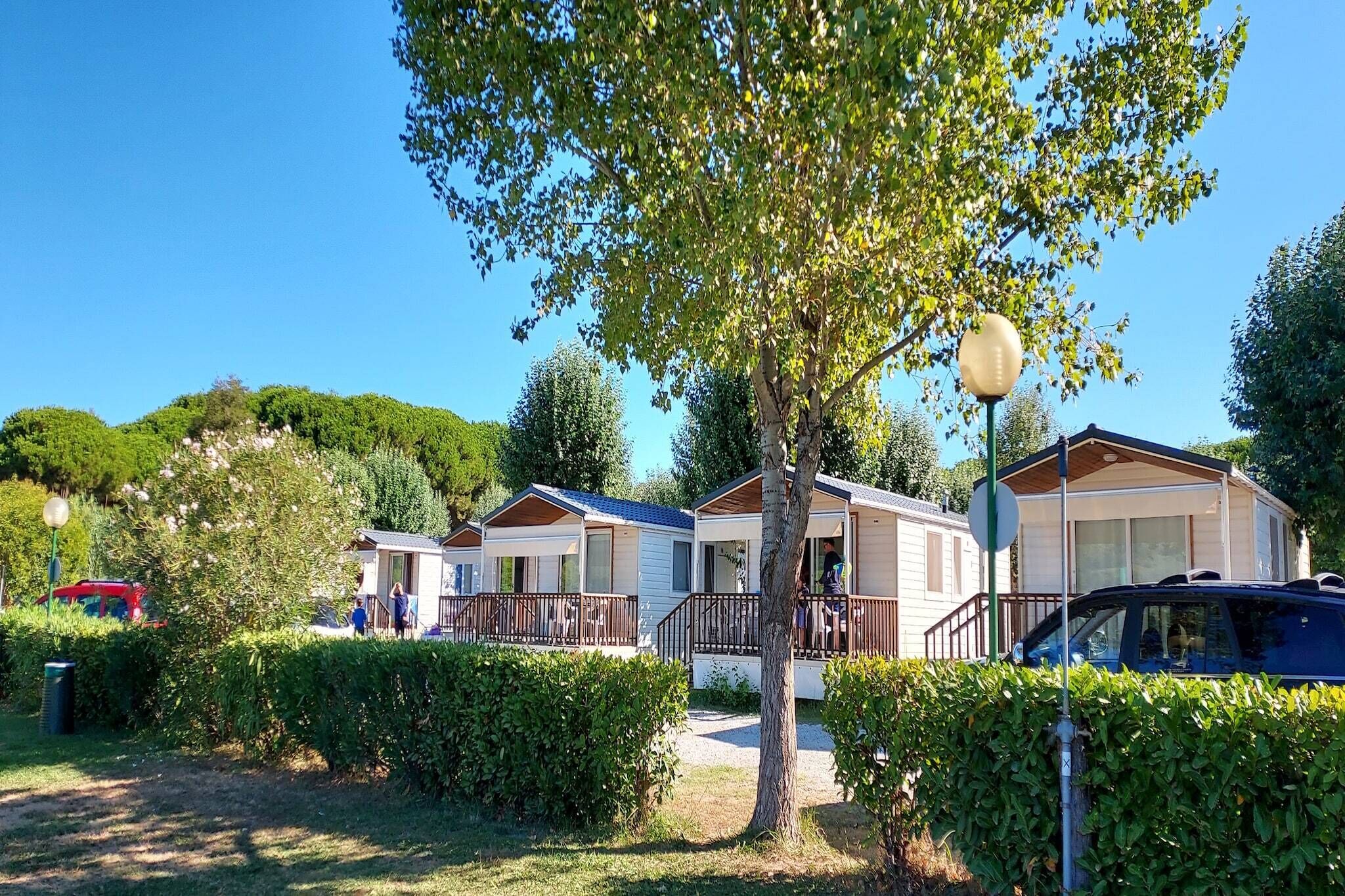 Una fila di case mobili con un vialetto lastricato che le separa, circondate dal verde e sotto un cielo sereno.