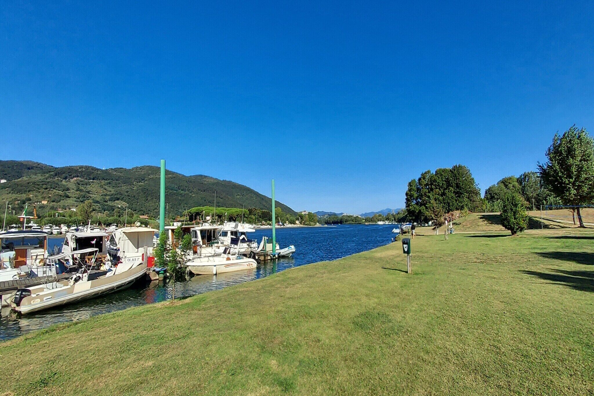 Una marina con imbarcazioni ormeggiate, sponde erbose e un cielo azzurro limpido.