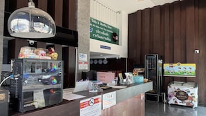 Zona de recepción de hotel con una pantalla digital, un cartel de prohibido fumar y un letrero que indica tarifas diarias y mensuales.
