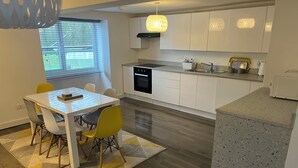 Een moderne keuken met witte kastjes, een ingebouwde oven en een granieten aanrecht.