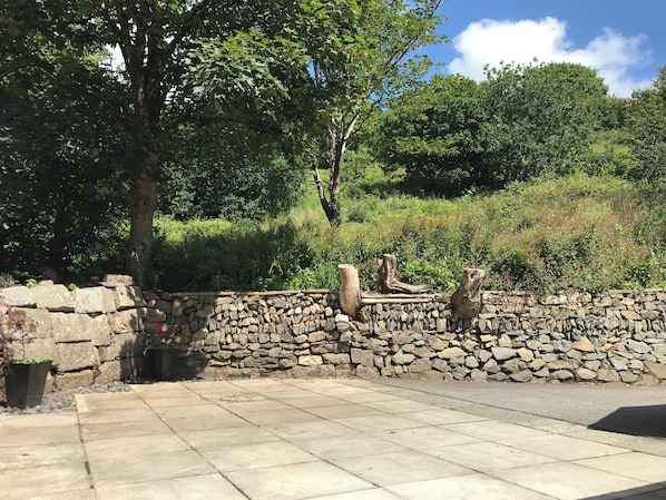 Un muro de piedra con un sendero de piedra que lleva a una zona cubierta de césped y árboles.