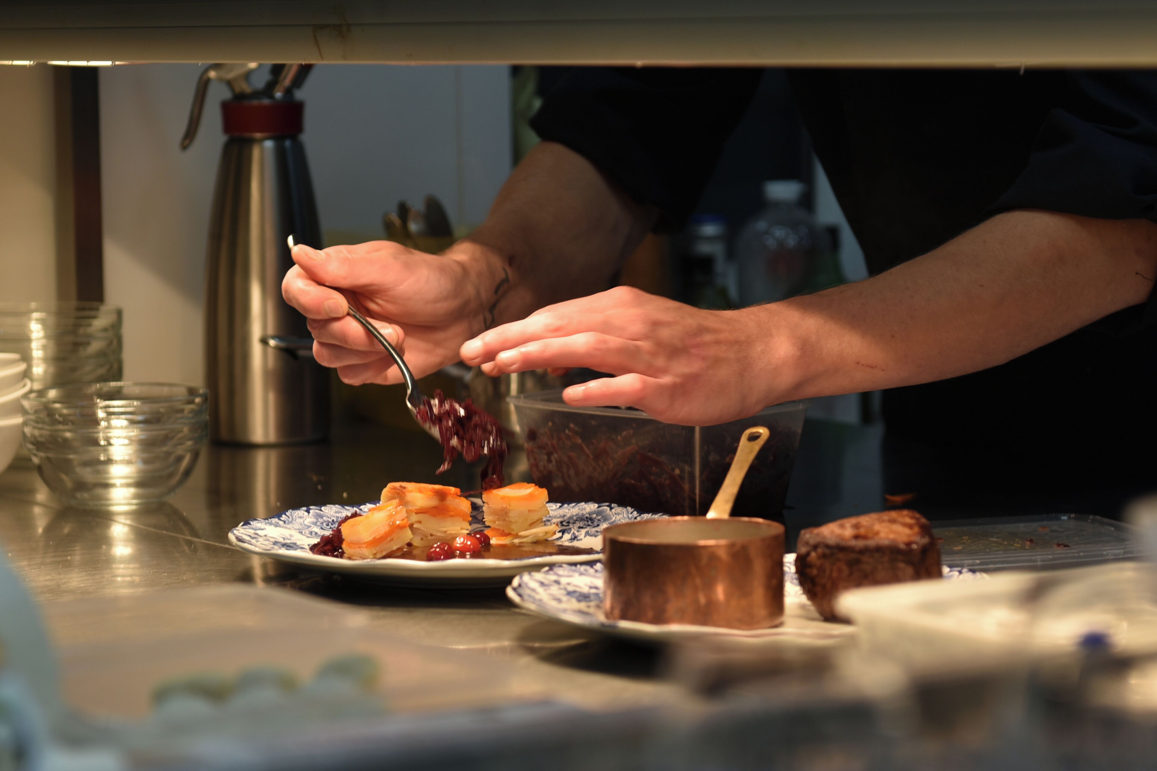 Una persona sirve comida desde un recipiente transparente a un plato.