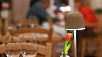 Una mesa de comedor con cristalería transparente y un florero con una sola tulipán.