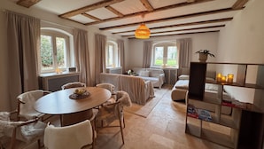 A cozy room with a wooden ceiling, a round dining table, white chairs, a sofa, and a bookshelf. - Family- & dog-friendly apartment near the Elbe with direct access to the park (Dresden)