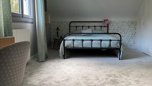 Quarto com cama, cadeira, abajur e luminária pendente.