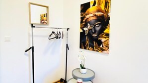 A room with a wooden floor, a black coat rack, a framed picture on the wall, and a small table with a vase of flowers. - 5 Bedroom Apartment near Schonbrunn (Vienna)