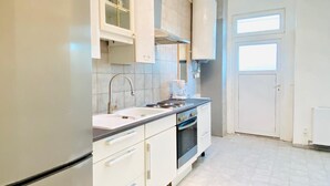 A modern kitchen with white cabinetry, a built-in oven, a refrigerator, and a window. - 5 Bedroom Apartment near Schonbrunn (Vienna)