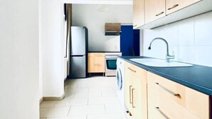 A modern kitchen with wooden cabinets, a black countertop, and a built-in washing machine. - Budget Friendly 4 BR Apt for Groups (Vienna)