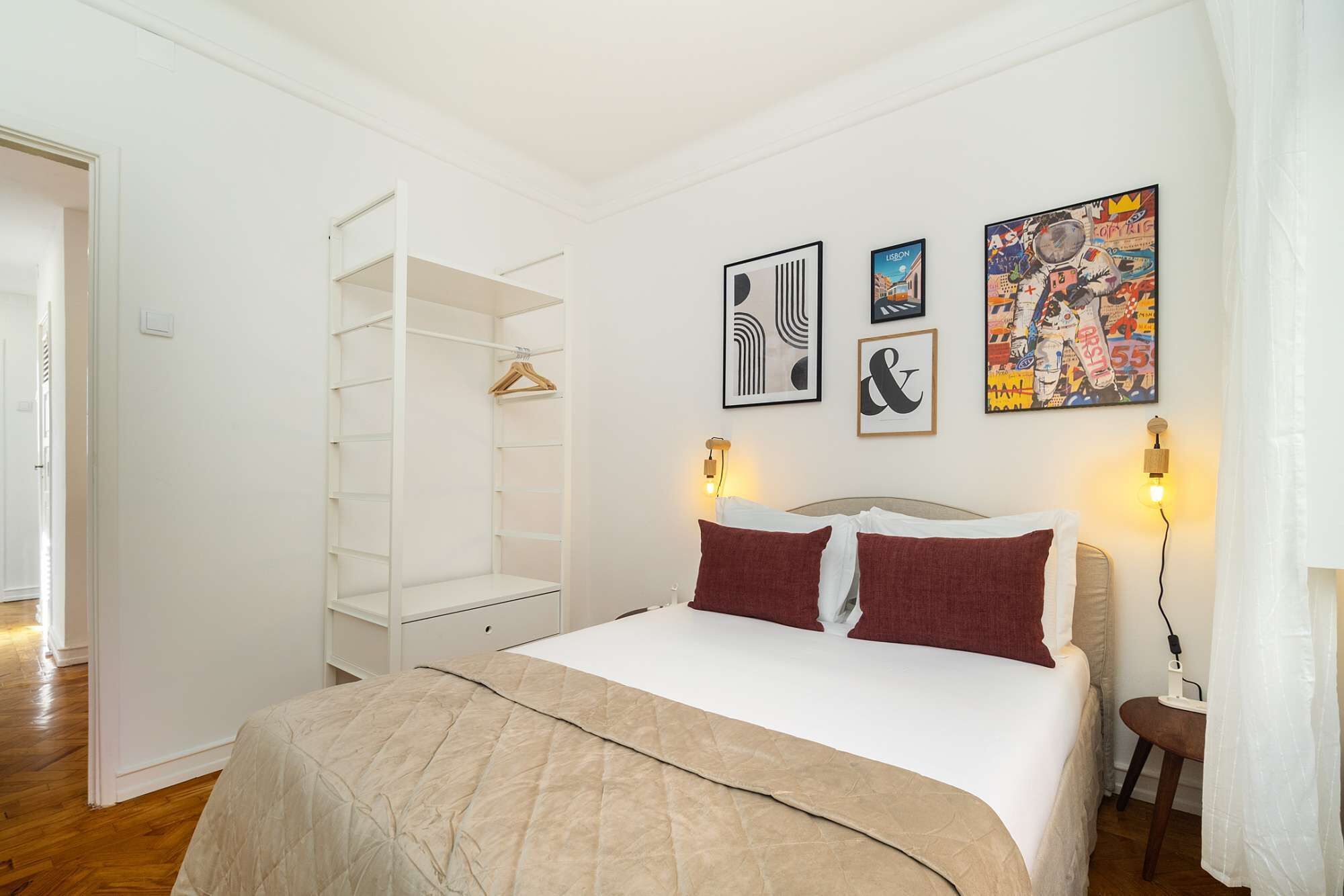 Ein Schlafzimmer mit einem Bett, einem Kleiderschrank und drei an der Wand befestigten Kunstwerken.