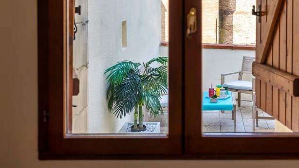 A view through a wooden door of a balcony with a table, chairs, and potted plants. - House T3 Gaillac Centre-Cosy-Netflix-Parking (Gaillac)