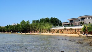 A beach with clear water, a sandy shore, and buildings in the background. - Spacious 5-bedroom villa in serene Privlaka with all year swimming pool (Privlaka)