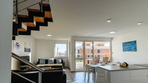 A modern kitchen with a central island, a dining area with a table and chairs, and a staircase leading to an upper level. - Spacious 5-bedroom villa in serene Privlaka with all year swimming pool (Privlaka)