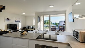 A modern kitchen with a large island, a dining area with a table set for four, and a view of the outdoors through large windows. - Spacious 5-bedroom villa in serene Privlaka with all year swimming pool (Privlaka)