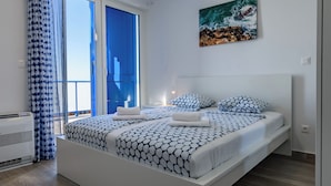 A modern bedroom with a large bed, a balcony, and a painting of a beach scene. - Spacious 5-bedroom villa in serene Privlaka with all year swimming pool (Privlaka)