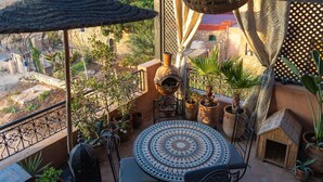Ein gemütlicher Balkon mit rundem Tisch, Blumentöpfen und dekorativer Wand.