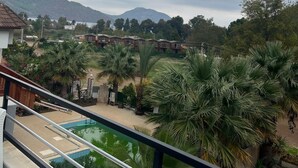 A balcony with a view of a swimming pool, palm trees, and a distant mountain range under a cloudy sky. - Eldorado Hotel (Kumluca)