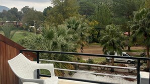 A balcony with two chairs and a table, overlooking a lush green landscape with trees and a distant hill. - Eldorado Hotel (Kumluca)