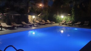 A nighttime swimming pool with lounge chairs and palm trees in the background. - Eldorado Hotel (Kumluca)