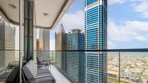 A balcony with modern chairs, a glass railing, and a view of high-rise buildings. - Paramount Hotel Rooftop Infinity Pool (Dubai)