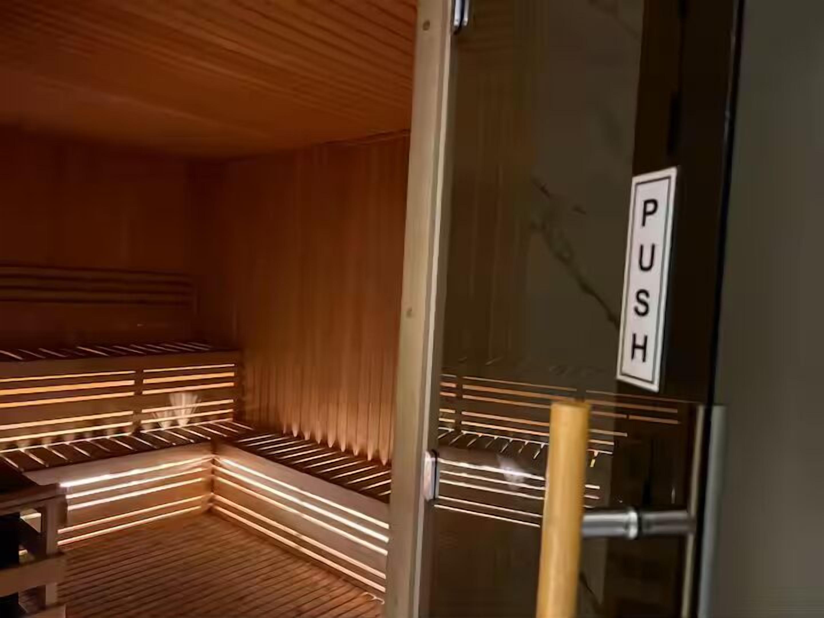 A sauna with wooden benches and a glass door with a 'PUSH' sign.