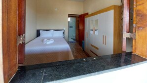Habitación de hotel con cama, armario y baño visible a través de una puerta abierta.
