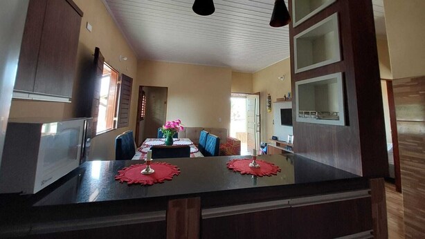 Una cocina moderna con una isla central, luces colgantes y un comedor con mesa y sillas.