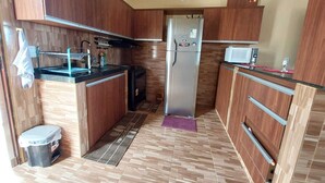 Una cocina compacta con armarios de madera, un refrigerador de acero inoxidable, un microondas y un lavamanos.