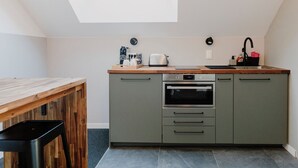 Een compacte keuken met dakraam, een houten tafel en een moderne oven.